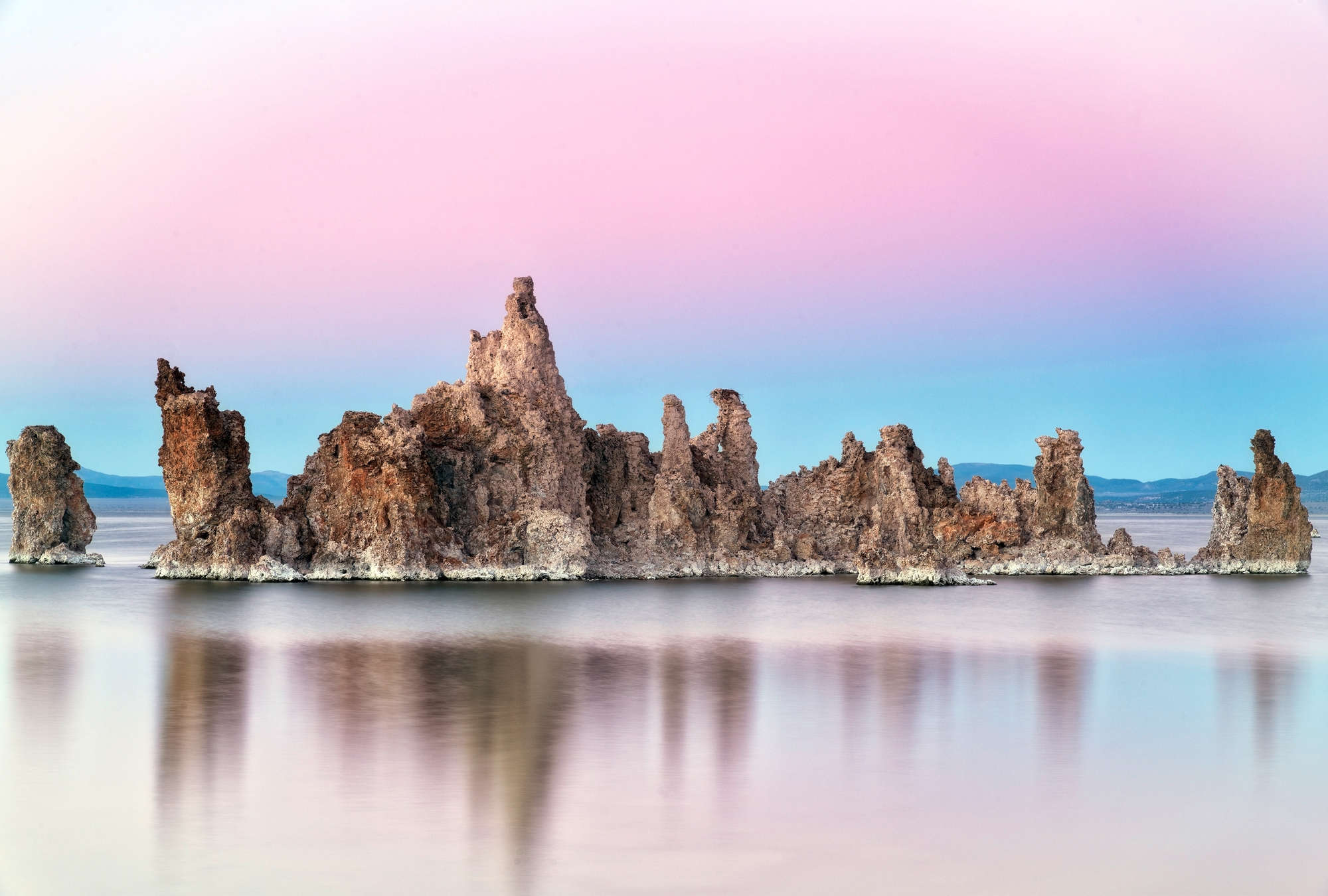            Fototapete Felsen im spiegelndem Wasser mit rosa Himmel
        